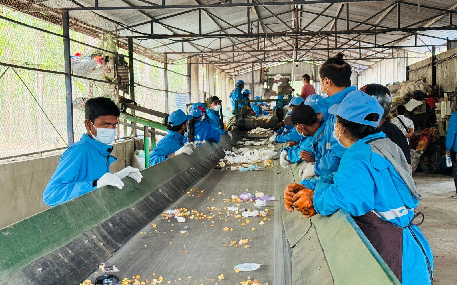 Operarios clasificando material reciclable en una banda de separación