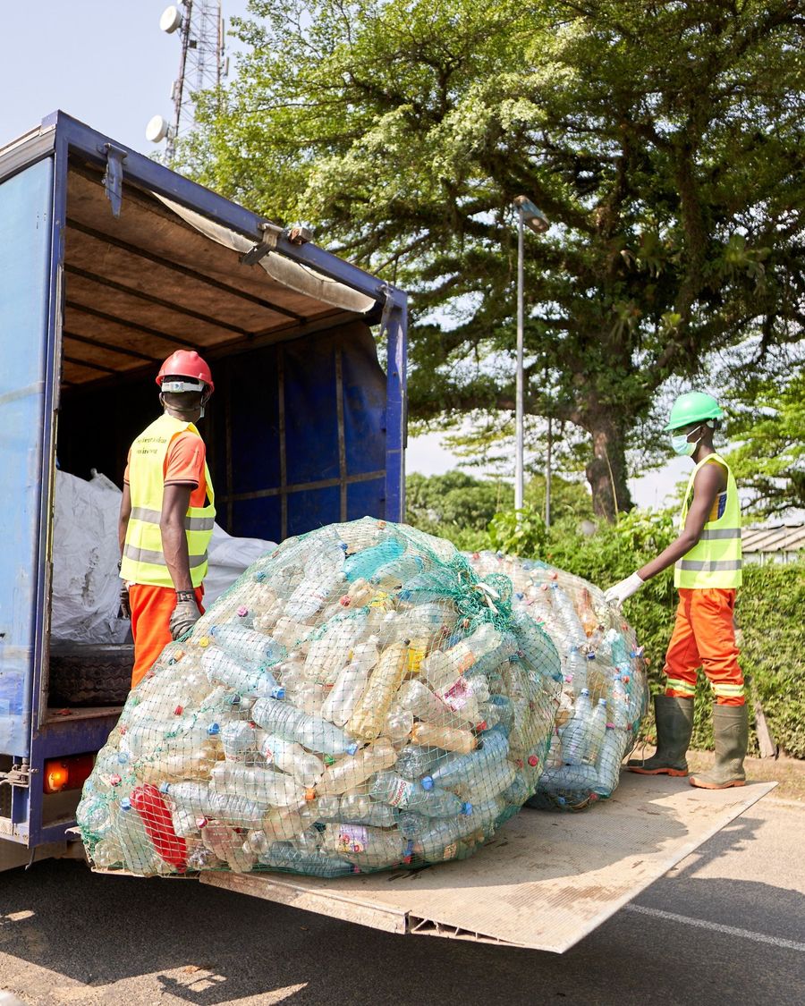 Equipo cargando sacos de botellas PET en un camión de recolección